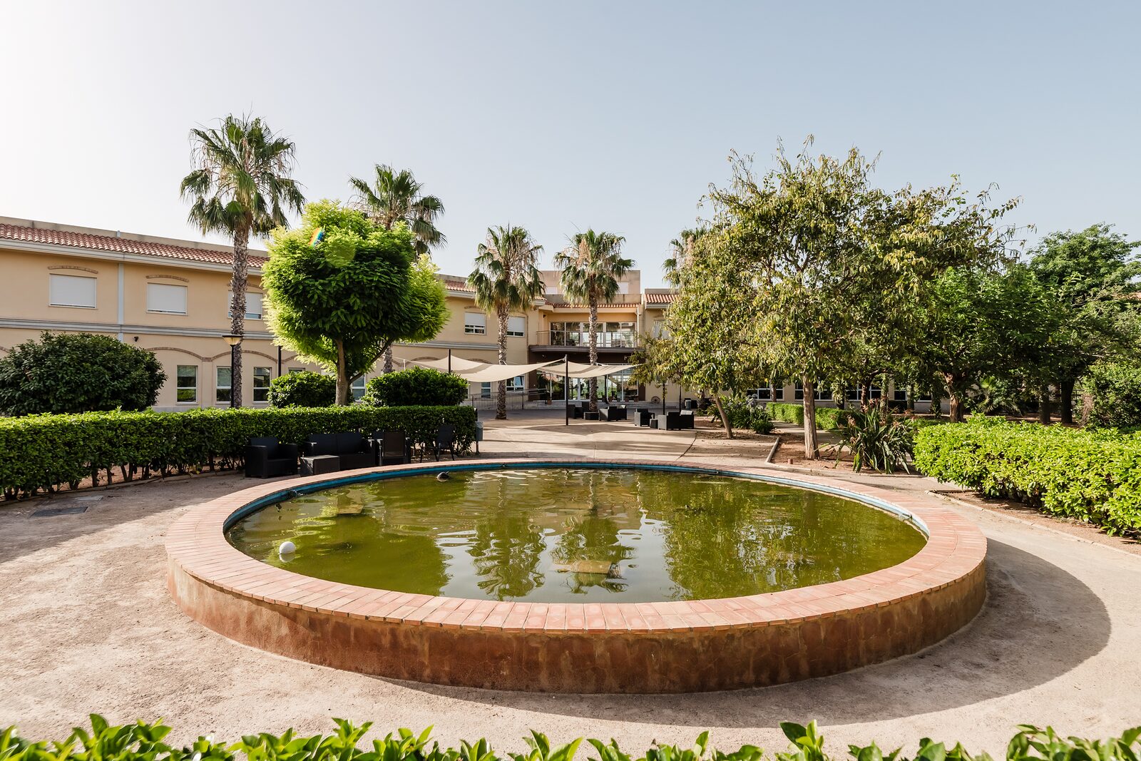 Fuente y jardín con la fachada de la residencia al fondo