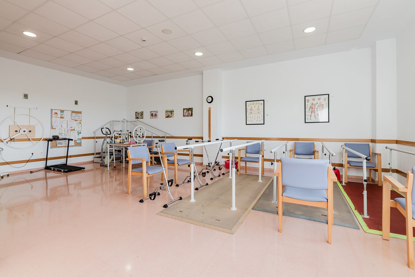 Sala de rehabilitación con barras paralelas y equipamiento de fisioterapia